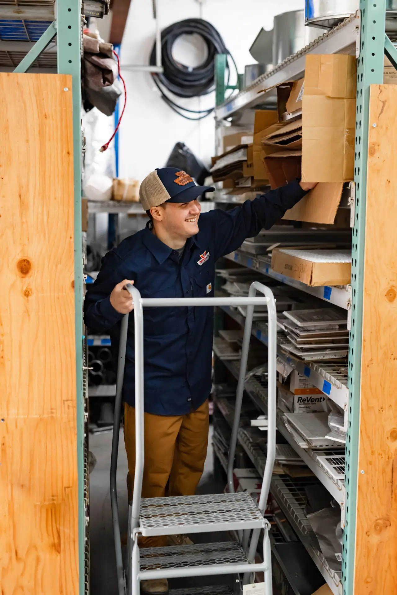 Warehouse worker reaching for box on shelf