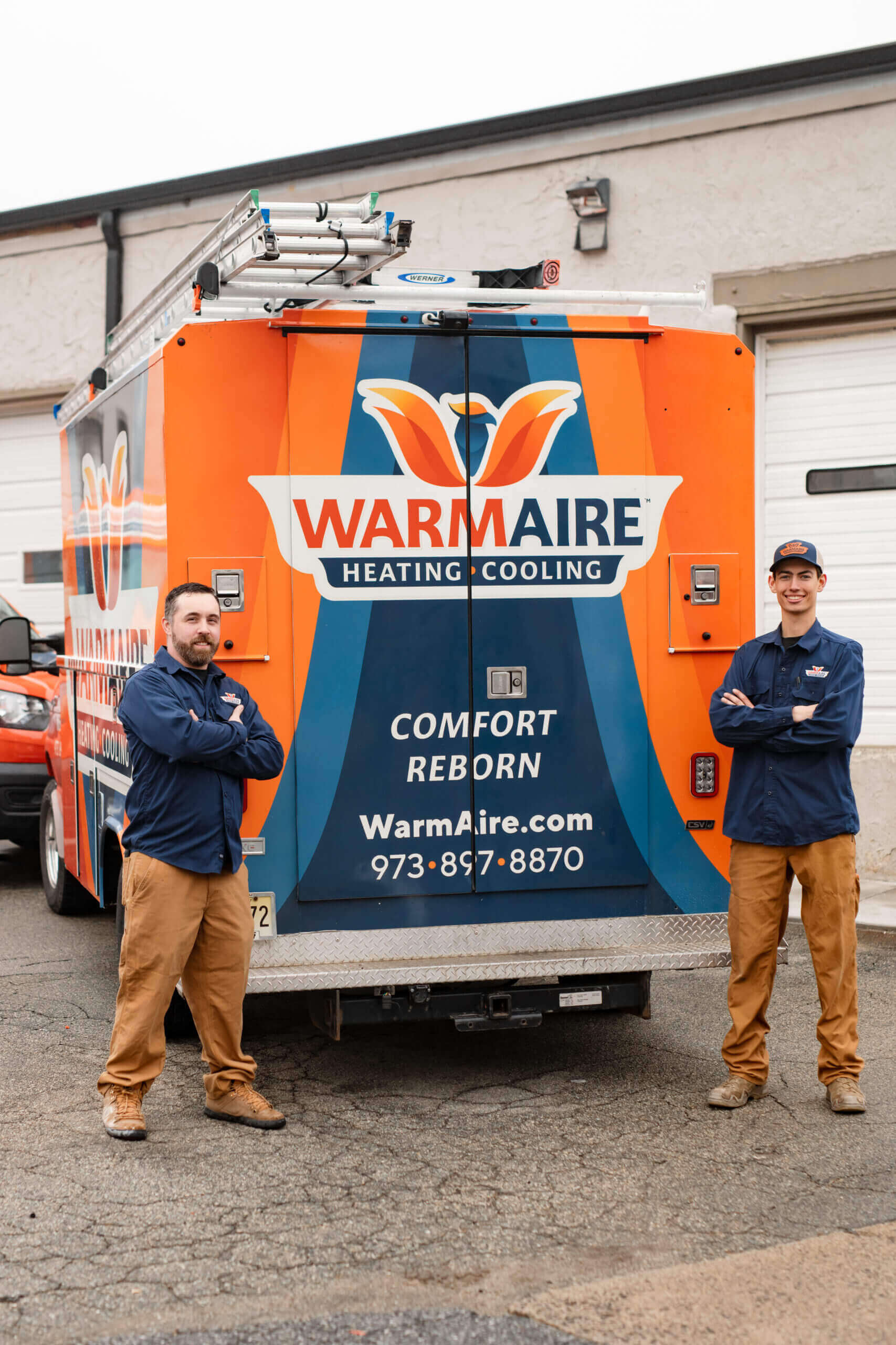 Two technicians standing by service truck.