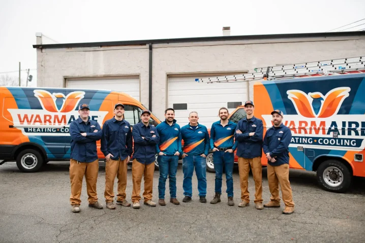 HVAC technicians standing between branded service vans